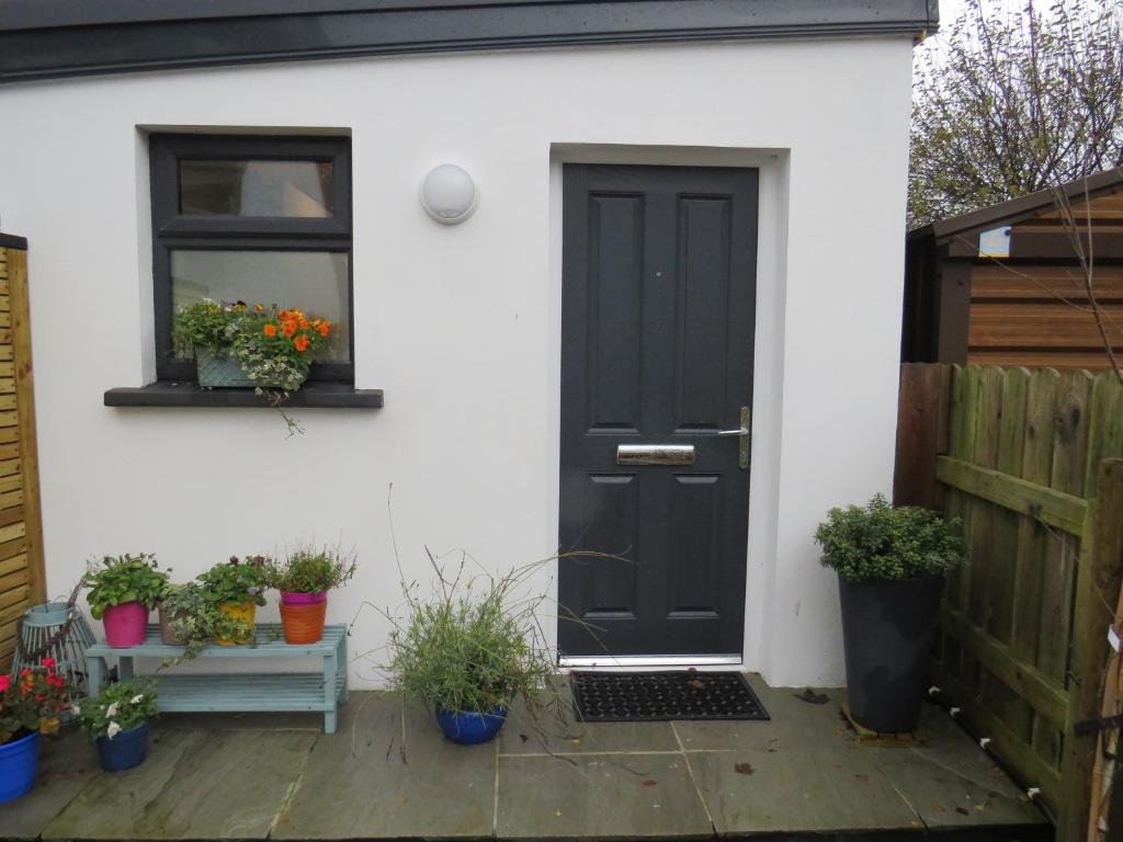 a black door on a white house with potted plants at Lavender Mews in Tuam
