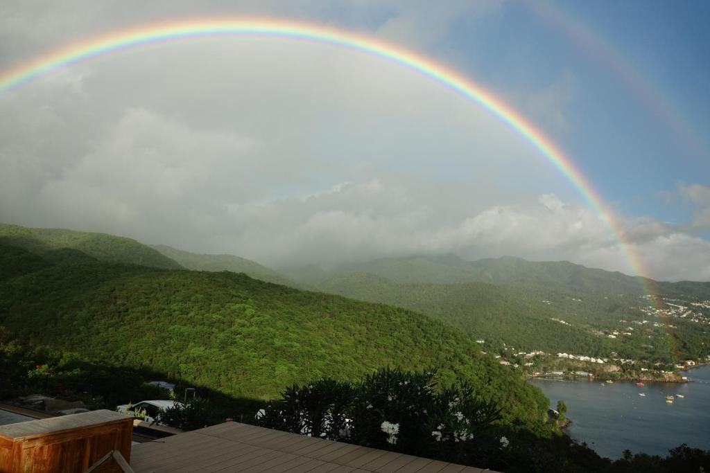 un arc-en-ciel au-dessus de l'eau et d'une ville dans l'établissement LES HAUTS DE LA BAIE, à Bouillante