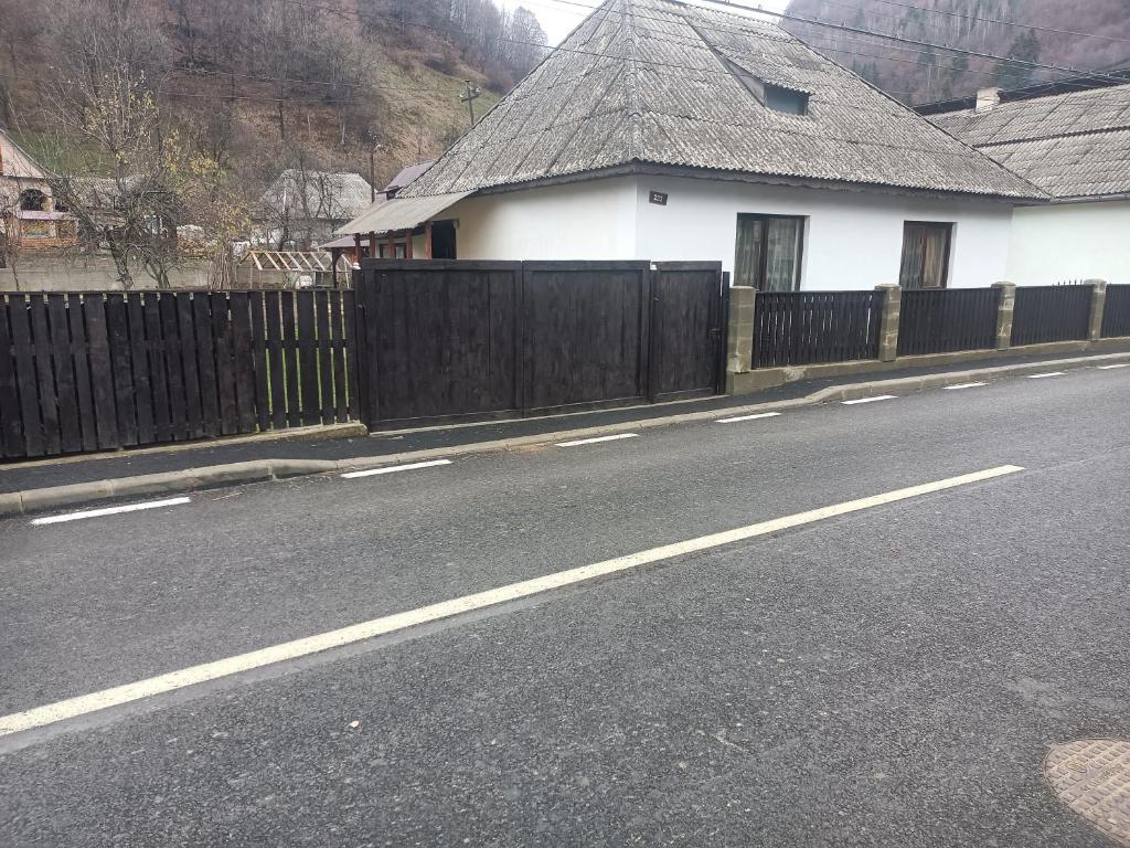 a white house with a wooden fence next to a street at Casa Simona in Vişeu de Sus