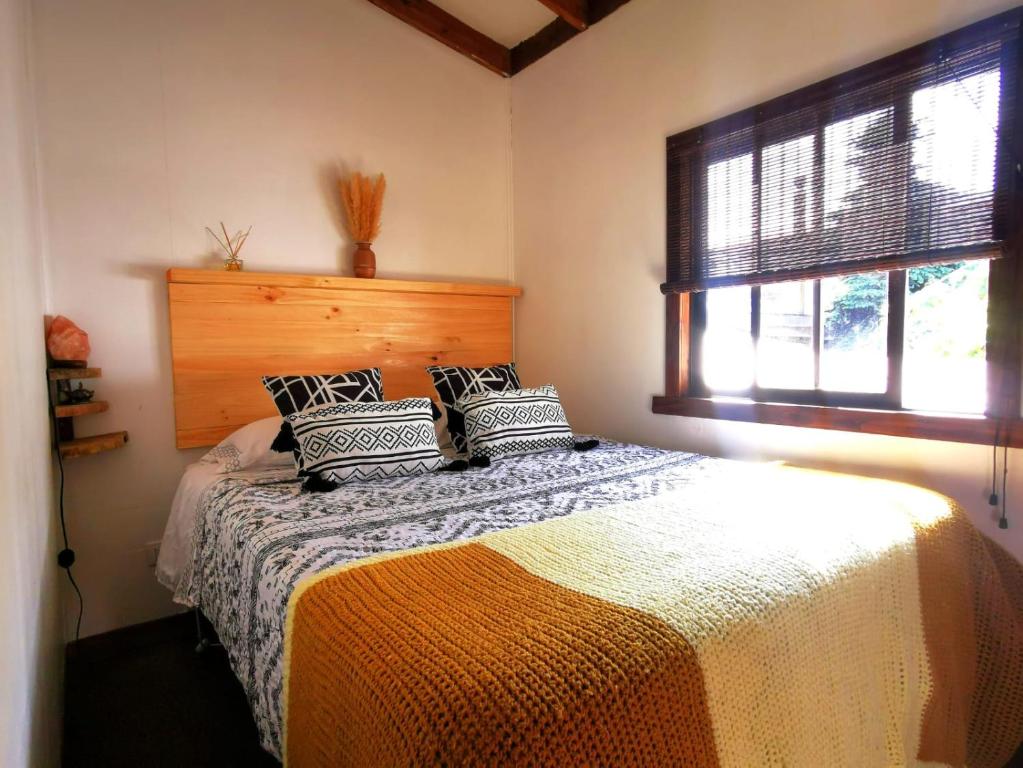 1 dormitorio con 1 cama en una habitación con ventana en Kimün Rise Cabaña Céntrica Villarrica en Villarrica