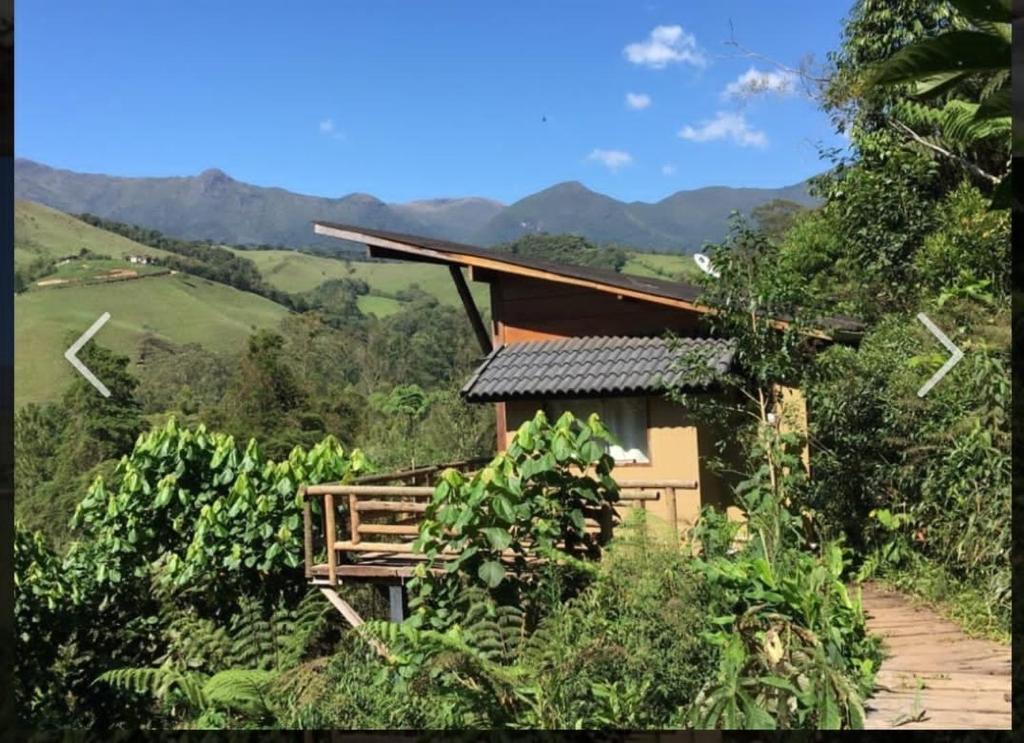 ein Haus auf einem Hügel mit Bergen im Hintergrund in der Unterkunft Villa Gatto Chalés - Visconde de Maua in Bocaina de Minas