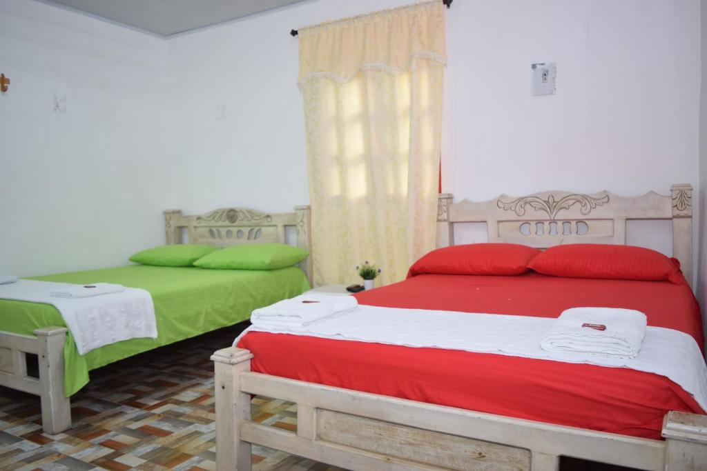 1 Schlafzimmer mit 2 Betten in Rot und Grün in der Unterkunft HOSTAL LA MACARENA in El Zaino