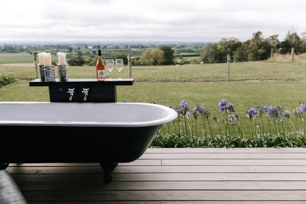 a bath tub sitting on a deck with a view of a field at Birds Eye View in Havelock North