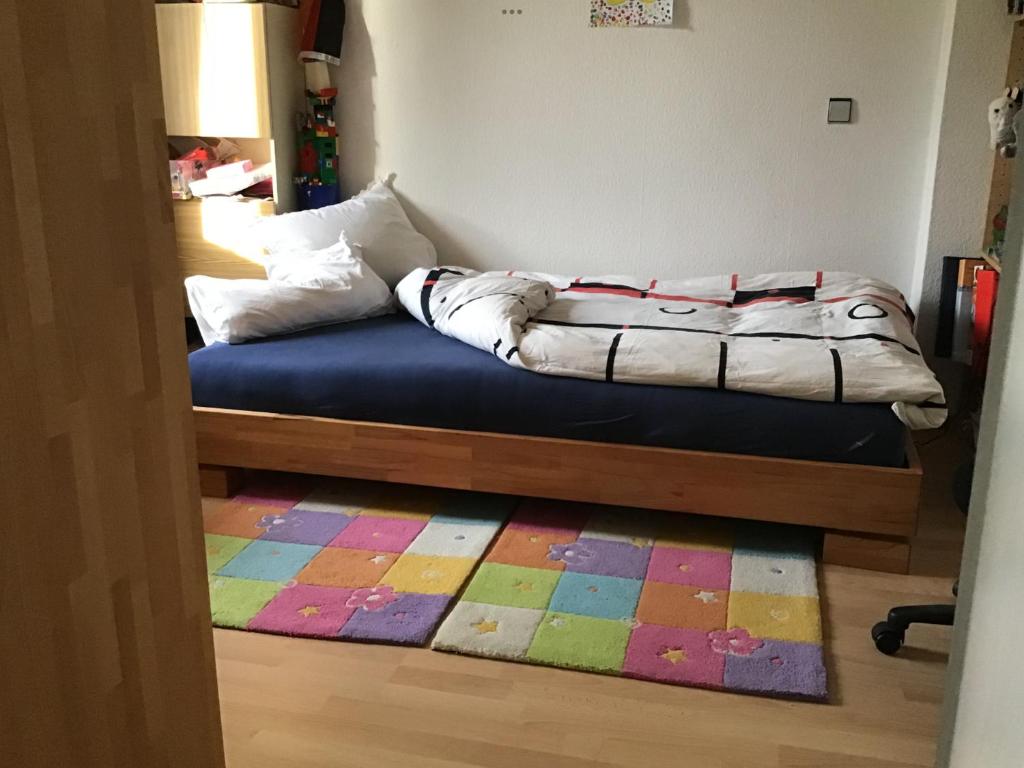 a bed in a room with a colorful rug at 2 Zimmer mit Verbindungstür, ruhig, Aussicht zum Garten und Weinbergsblick in Winningen