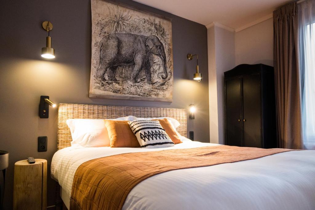 a bedroom with a bed with an elephant picture on the wall at Hotel Le Patio - Deauville in Deauville