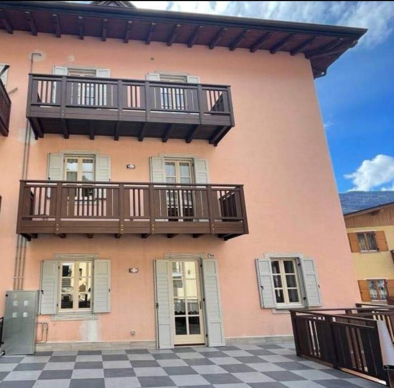 różowy budynek z balkonem i podłogą wyłożoną szachownicą w obiekcie Appartamenti ALICE MOLVENO w mieście Molveno