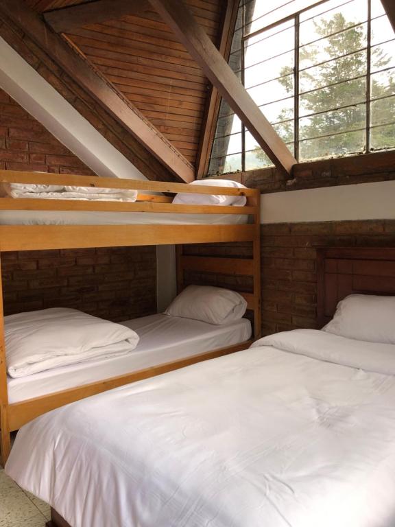 2 Etagenbetten in einem Zimmer mit Fenstern in der Unterkunft Mountain Chalet - Tungurahua Hot Springs/Aguas Termales in Baños
