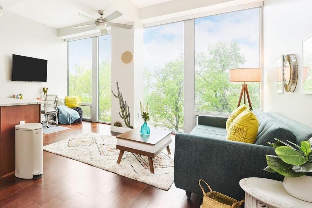 a living room with a blue couch and a large window at HostWise Stays - The Washington at Chatham - Free Parking, Private Gym, Skyline Views! in Pittsburgh