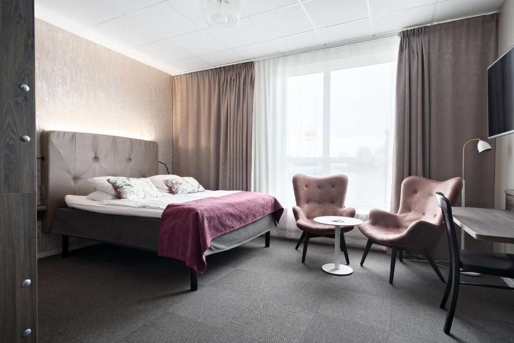 a bedroom with a bed and two chairs and a table at Best Western Hotell Ljungby in Ljungby