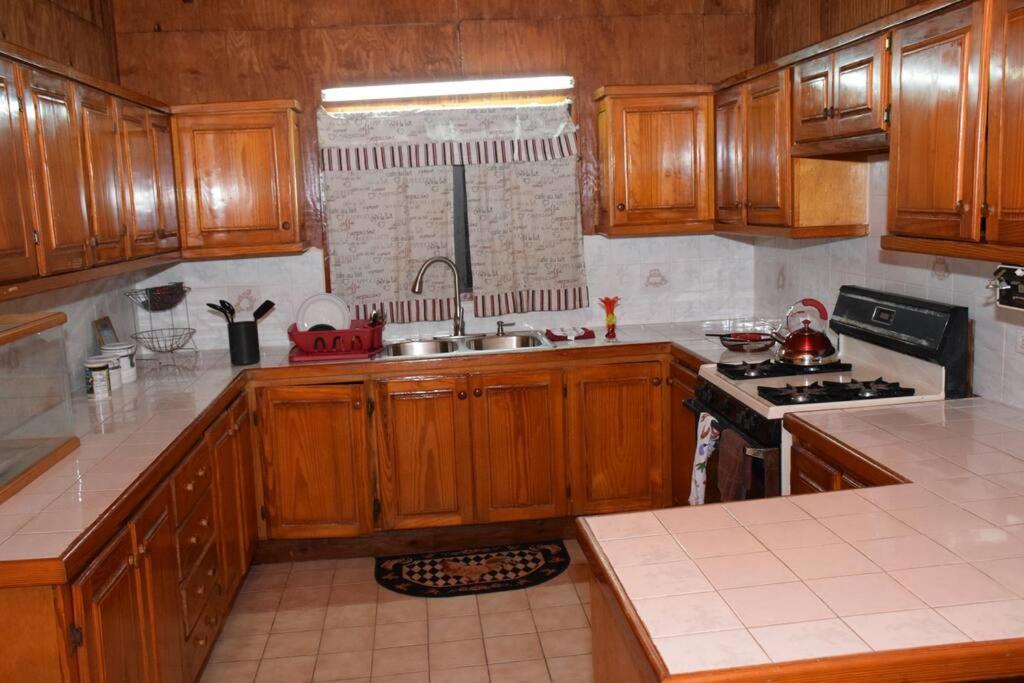 a kitchen with wooden cabinets and a sink and a stove at Maggie's Guest House/10 Min Walk to City- Certified in Branns Hamlet