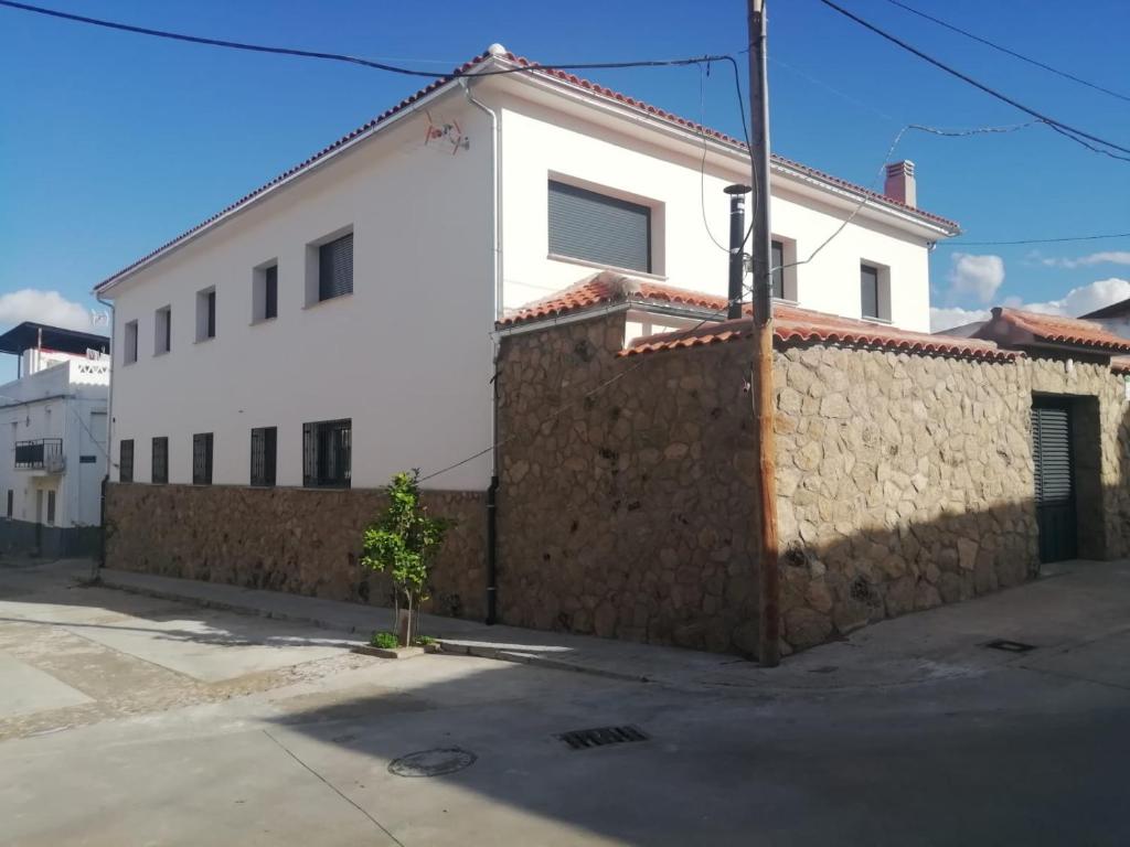 a white house with a stone wall next to a street at Casa Rural Feymar 