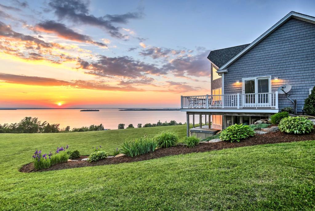 a home with a view of the ocean at sunset at Waterfront Lake Champlain Home with Hot Tub and Sauna! in Melville Landing