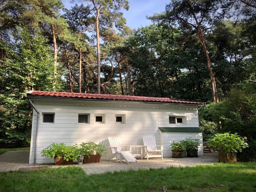 a white shed with two chairs and a table at Tranquil bungalow in Lille with garden in Lille