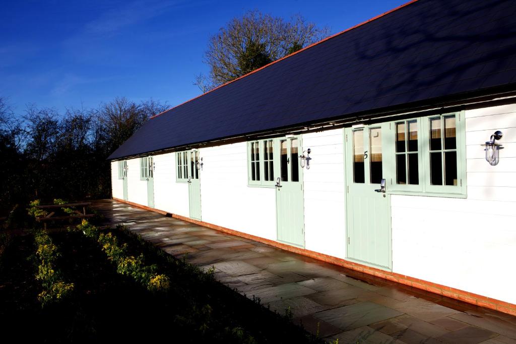 a white building with windows and a black roof at The Bull Inn Lodges in Tenterden