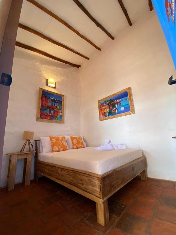 a bed in a room with two pictures on the wall at El Principito Hospedaje in Barichara