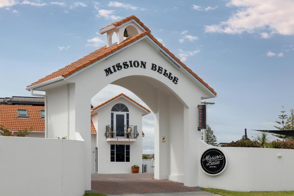 un bâtiment blanc avec un panneau indiquant la maison de la mission dans l'établissement The Mission Belle Motel, à Mount Maunganui