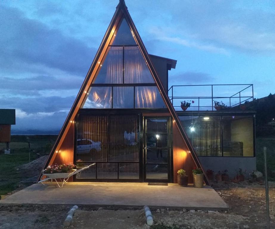 una casa con techo triangular con luces encendidas en Glamping y Cabañas el Encanto-Girasoles, en Tota