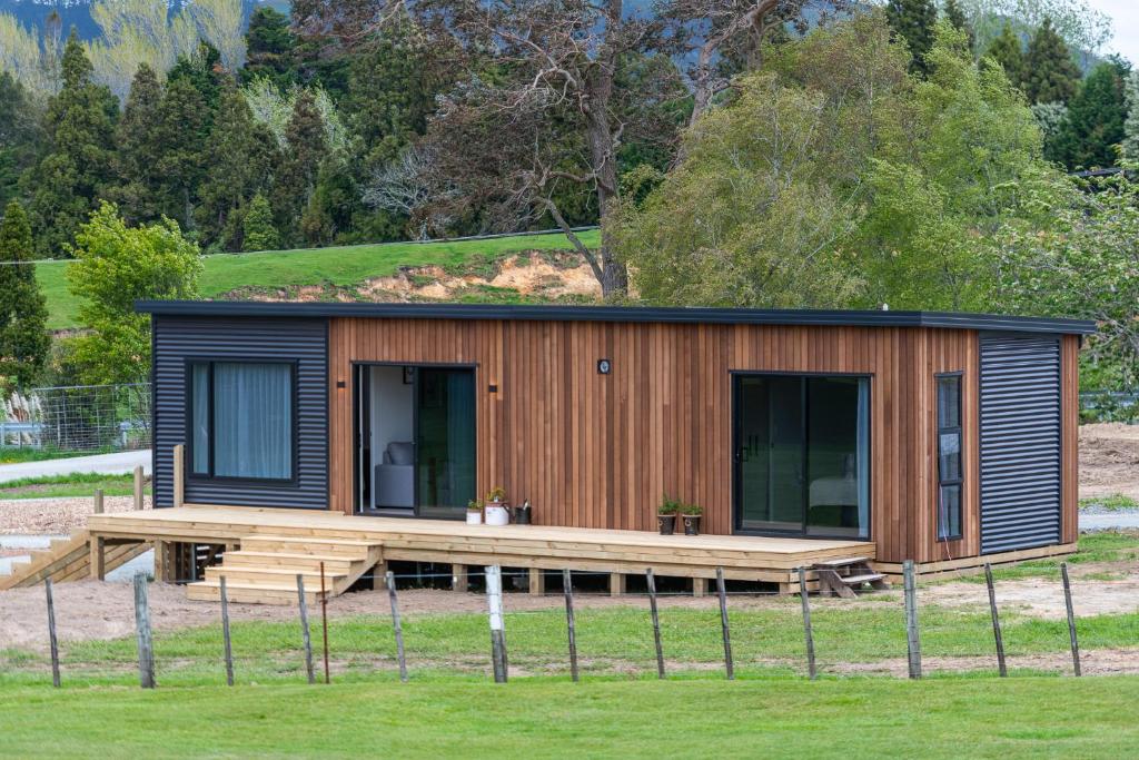 a tiny house with a deck in a field at Fairway Cottages in Rotorua