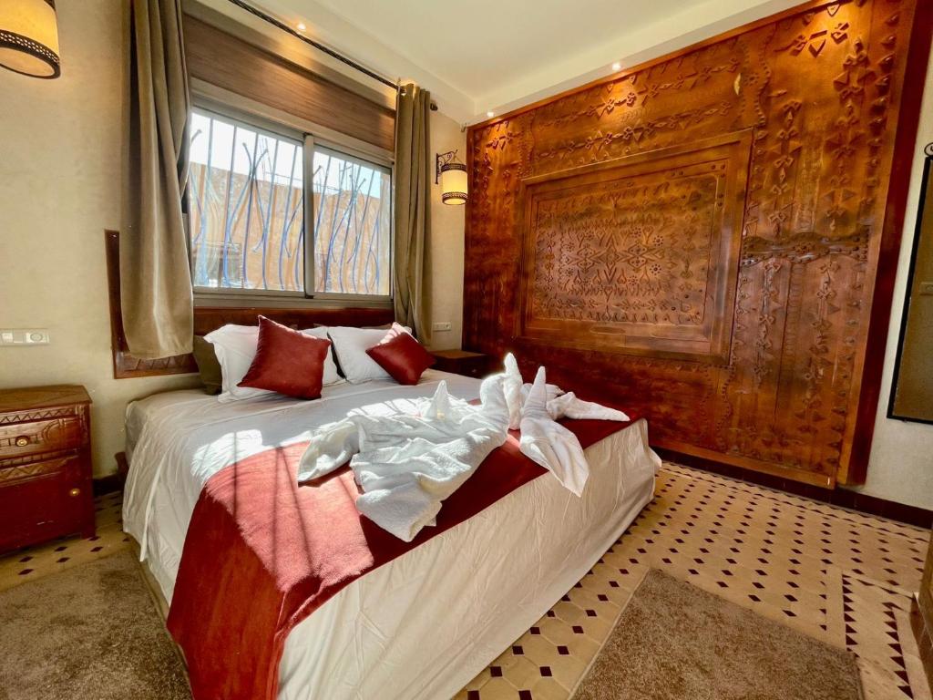 a bedroom with a bed with a large wooden headboard at Hotel Apartments Lexpert in Merzouga