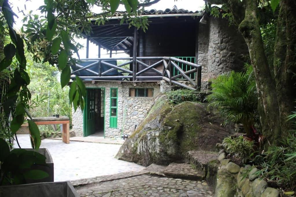 ein Steingebäude mit einer grünen Tür in einem Wald in der Unterkunft Chalet a orillas del rio Pance in Cali