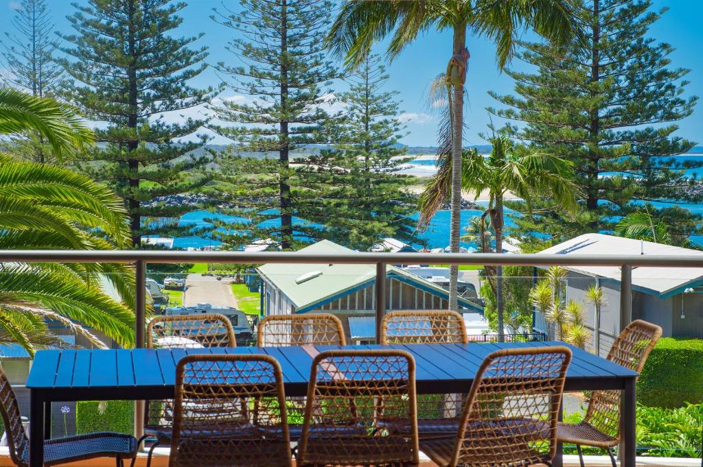 a blue table and chairs on a balcony with palm trees at Flightdeck 203 5-7 Clarence Street PM in Port Macquarie