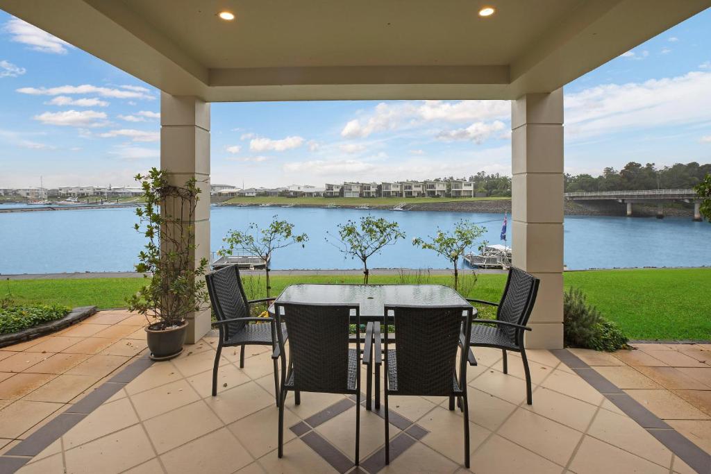 un patio con mesa y sillas con vistas al río en 22 The Promenade, en Port Macquarie