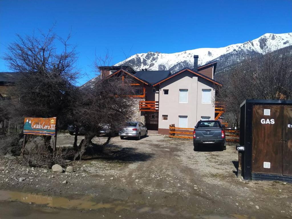 dom z samochodami zaparkowanymi przed nim z górą w obiekcie Villa Catedral w mieście Bariloche