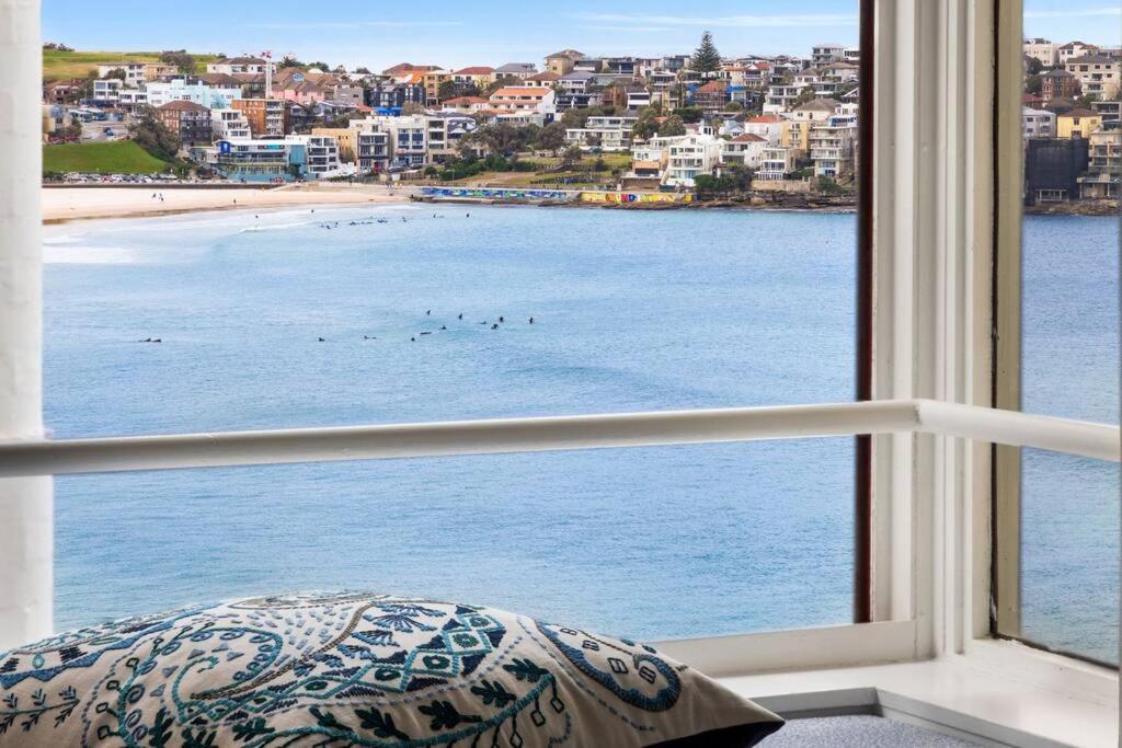 a window with a view of a beach and buildings at Studio Bondi Beach in Sydney