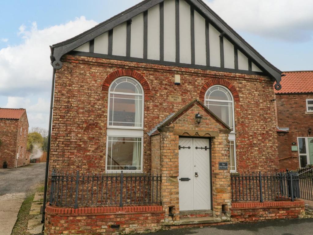 an old brick building with a white door at The Old Chapel in Bishop Wilton