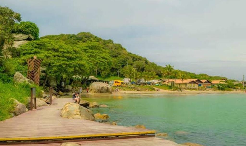 een houten promenade die leidt naar een meer met bomen en huizen bij Ap 203 - Mônaco Residence - rua na Beira da Praia - Não aceita pet in Florianópolis