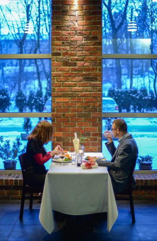 two people sitting at a table in a restaurant at Hotel Liburnia in Cieszyn