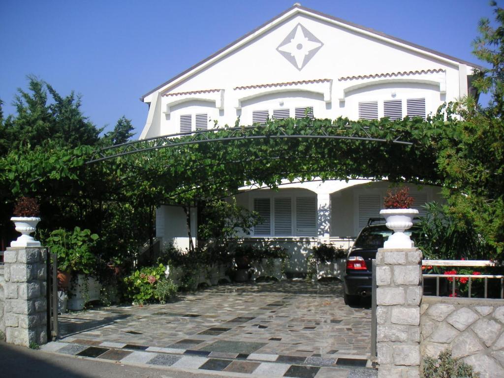 a white house with an arch over a driveway at Apartments Villa Mare in Krk