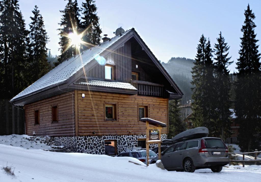 ein Blockhaus mit einem Auto im Schnee in der Unterkunft Apartmány Skihouse Jasná in Demänovská Dolina