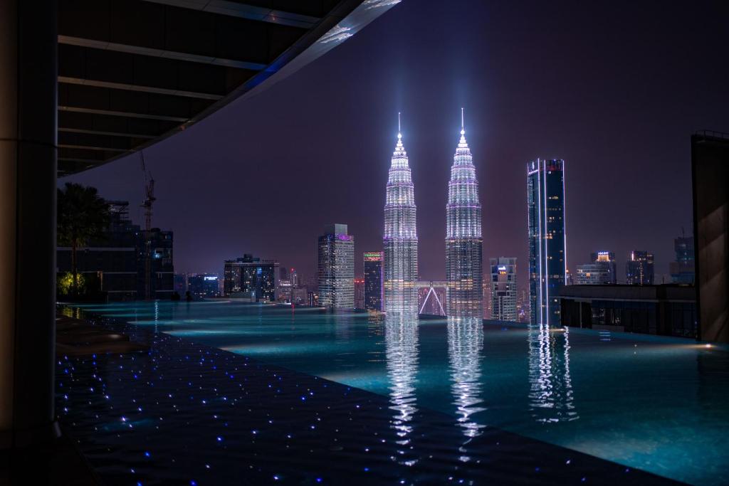 una piscina con vistas a la ciudad por la noche en Eaton Residences KLCC by Plush, en Kuala Lumpur