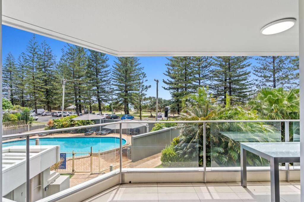 a balcony with a view of a swimming pool and trees at Solnamara - Hosted by Burleigh Letting in Gold Coast