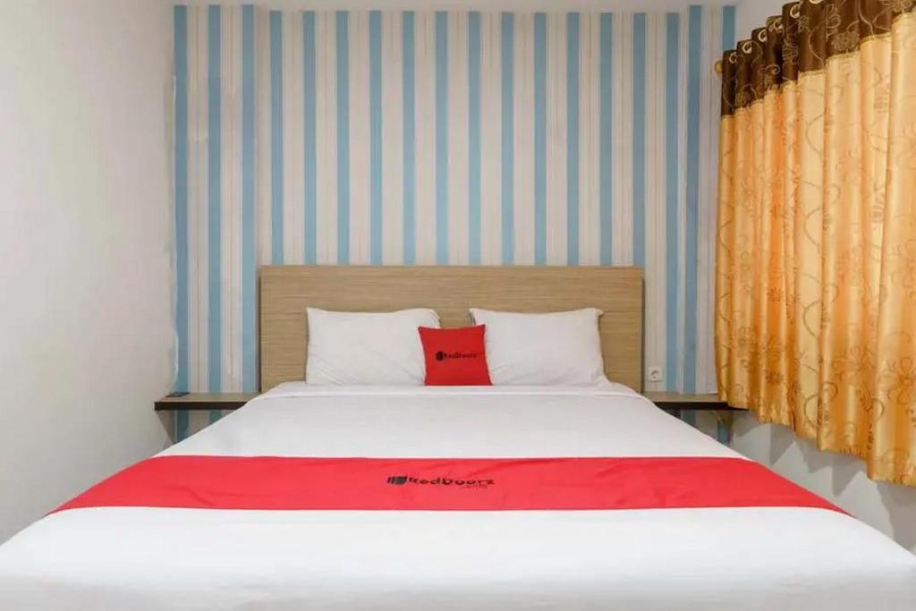 uma cama com duas almofadas vermelhas num quarto em RedDoorz Plus @ Cemara Asri Medan em Pulauberayan Dadap