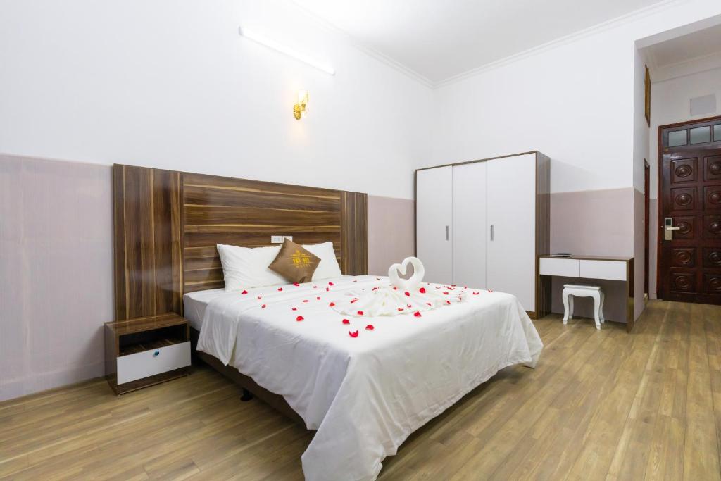 1 dormitorio con 1 cama con pétalos de rosa rojo en PHÚ QUÝ HOTEL near ĐÔNG KINH MARKET, en Lạng Sơn