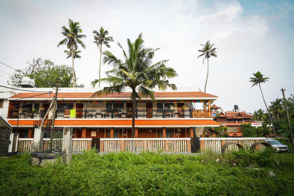 a building with palm trees in front of it at Aloha Homestay in Varkala