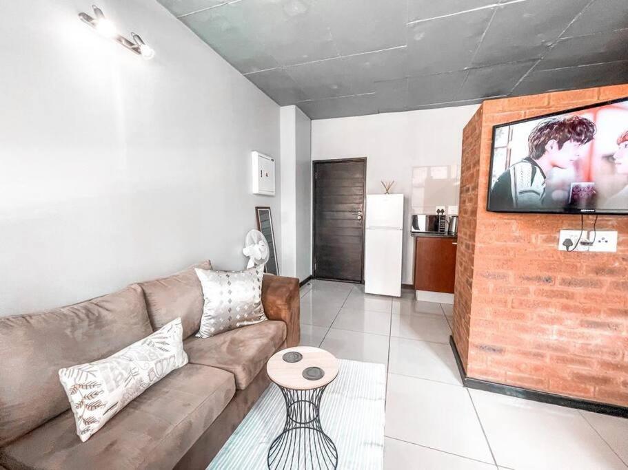 a living room with a couch and a flat screen tv at City living near Nelson Mandela bridge in Johannesburg
