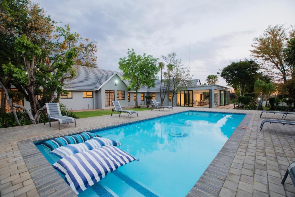 a swimming pool with blue water in front of a house at Naledi@53 Private Game Farm in Brits