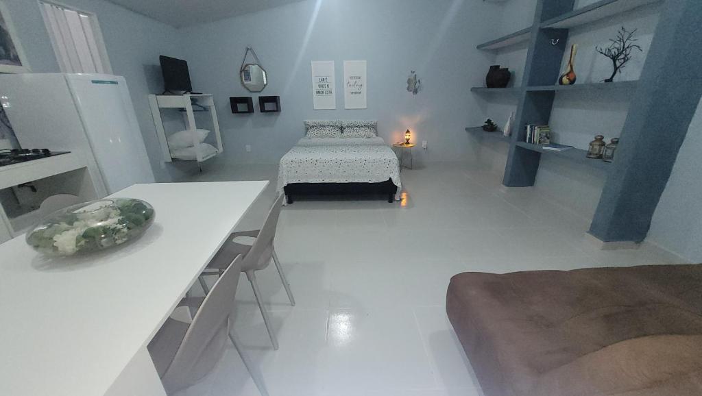 ナタールにあるLoft da Lilyのベッドとテーブル付きの広い白い部屋