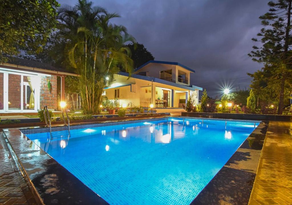 a swimming pool in front of a house at night at Garden Cottage Villa by Tropicana Stays in Lonavala