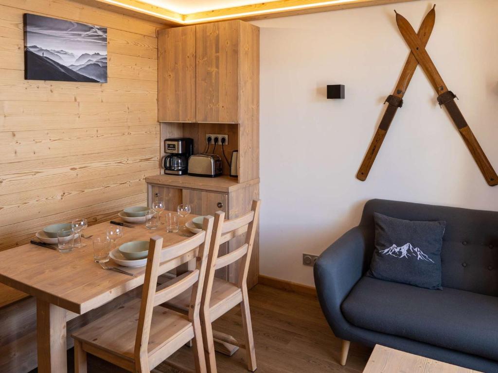 a dining room with a wooden table and a blue couch at Appartement moderne à Val Thorens - 4 pers - 1 chambre, 1 cabine, skis aux pieds, balcon - FR-1-637-30 in Val Thorens