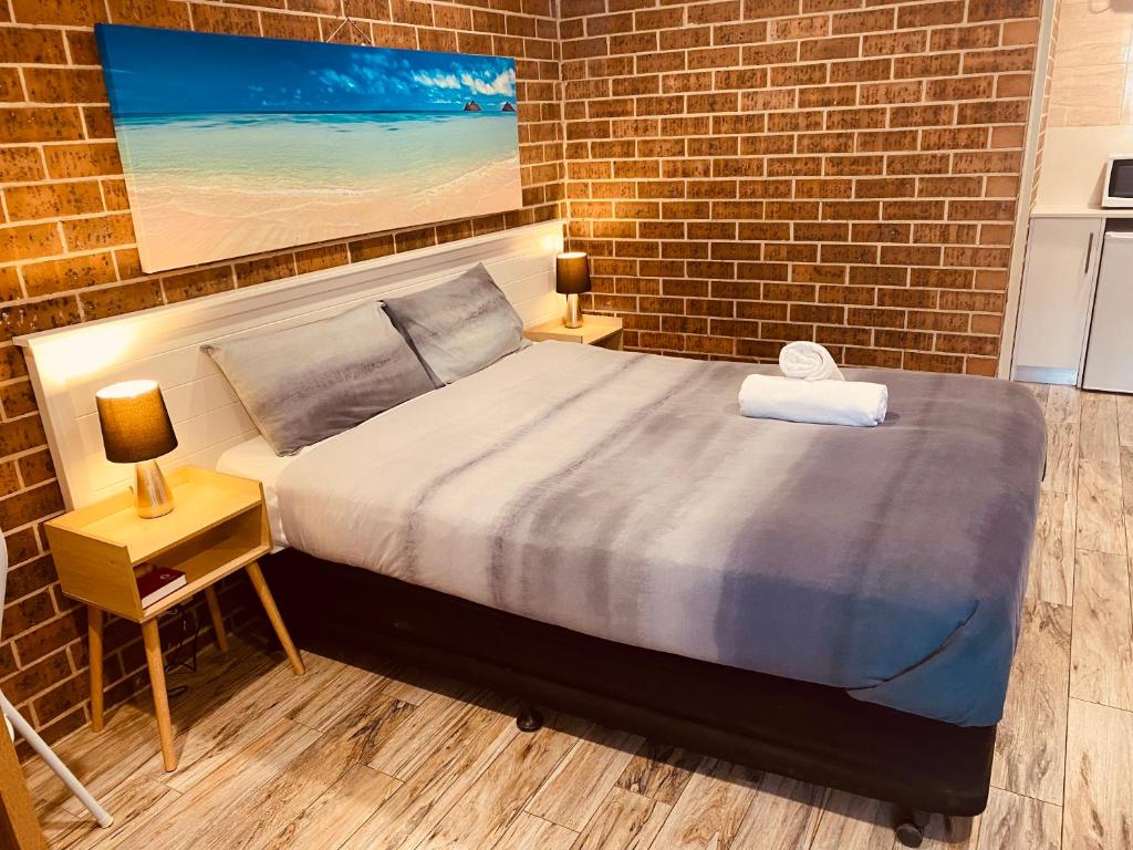 a bedroom with a bed and a brick wall at Buccaneer Motel in The Entrance