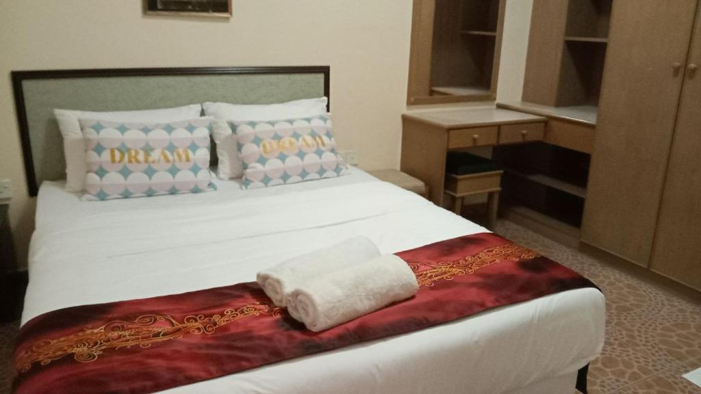 Un dormitorio con una cama blanca con una toalla. en Apartment Teluk Batik, en Lumut