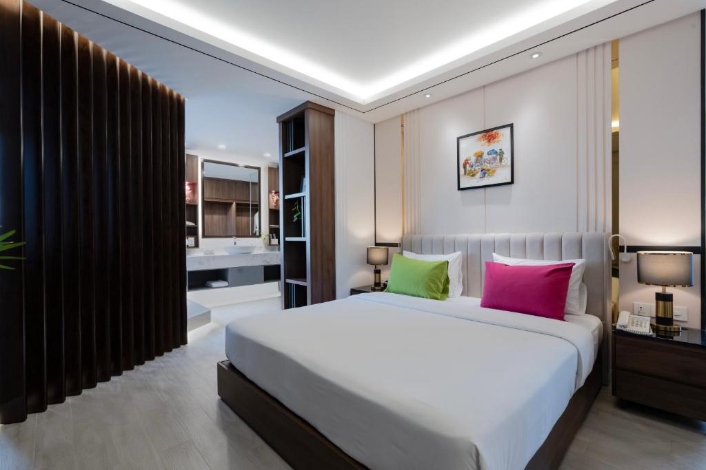 een slaapkamer met een groot bed met roze en groene kussens bij ÊMM Hotel Saigon in Ho Chi Minh-stad