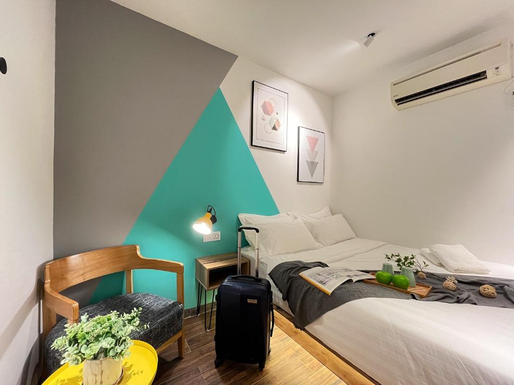 1 dormitorio con 2 camas y 1 maleta en Apple 1 Hotel Queensbay, en Bayan Lepas