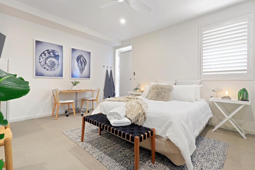 a white bedroom with a bed and a table at The Beach Studio in Huskisson