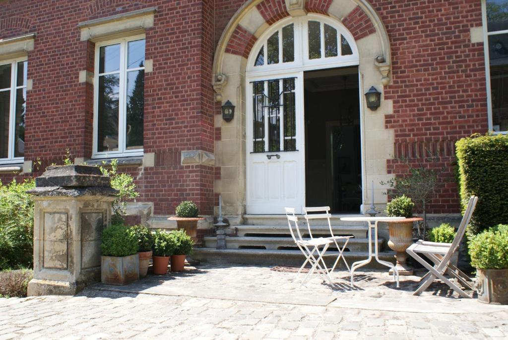 un edificio de ladrillo con una puerta blanca y sillas en Les Hortensias, en Clermont