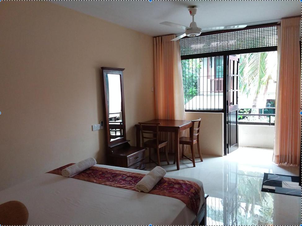 a bedroom with a bed and a table and a balcony at Colombo Residence in Colombo
